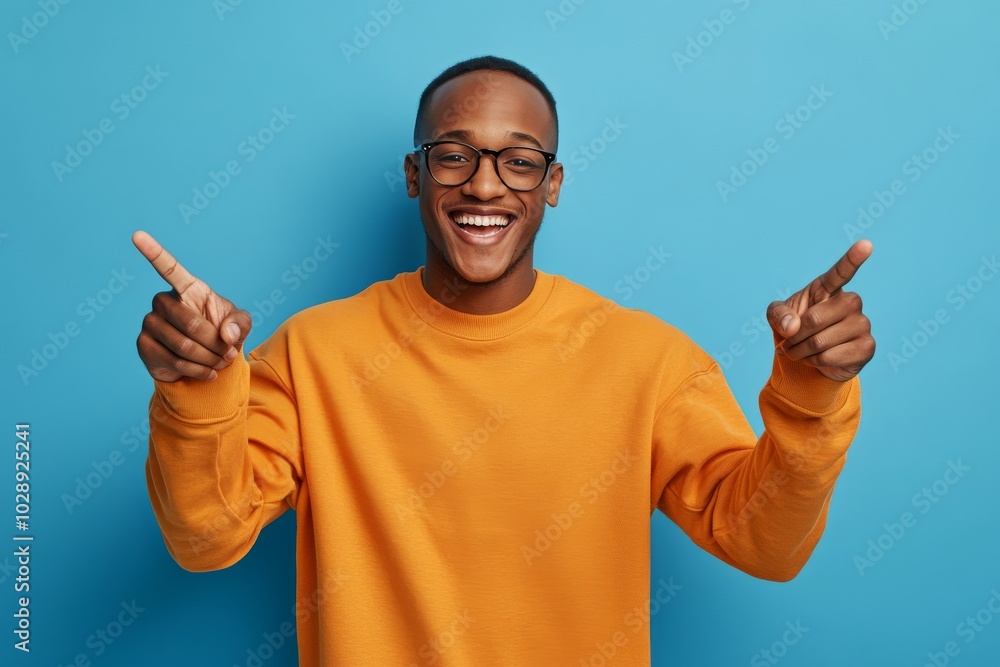 On a blue background, a young Russian man points forward with a positive expression. On a blue background, a young Russian man points forward with a positive expression.