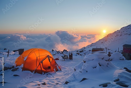 Captura un amanecer impresionante en una cadena montañosa, donde el sol emerge por encima del horizonte, iluminando las cumbres nevadas en tonos anaranjados y dorados. photo