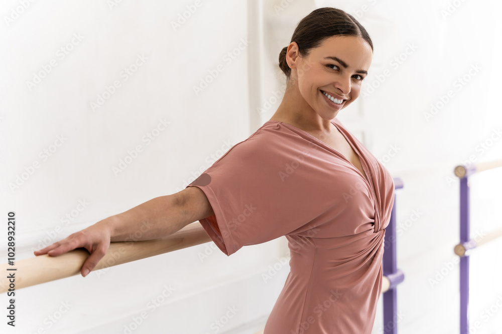Elegant female dancer in rehearsal hall practicing ballet poses at barre Elegant female dancer in rehearsal hall practicing ballet poses at barre