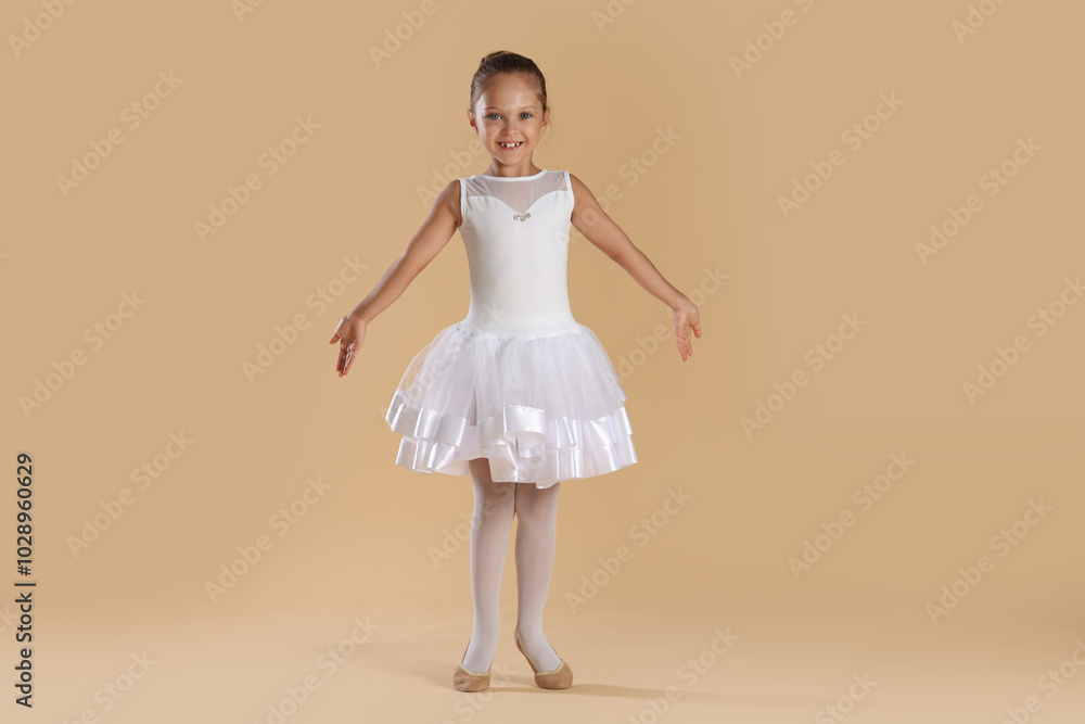 Naklejka premium Little ballerina practicing dance moves on beige background