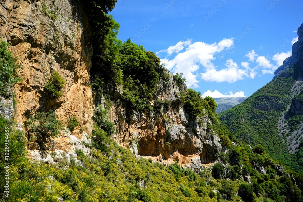 Panoramic view over the steep and green cliffs of the Vikos Gorge in Epirus, Greece on a summer's day. The gorge in the Pindus Mountains is one of the deepest gorges in the world. Hiking in Greece
Panoramic view over the steep and green cliffs of the Vikos Gorge in Epirus, Greece on a summer's day. The gorge in the Pindus Mountains is one of the deepest gorges in the world. Hiking in Greece