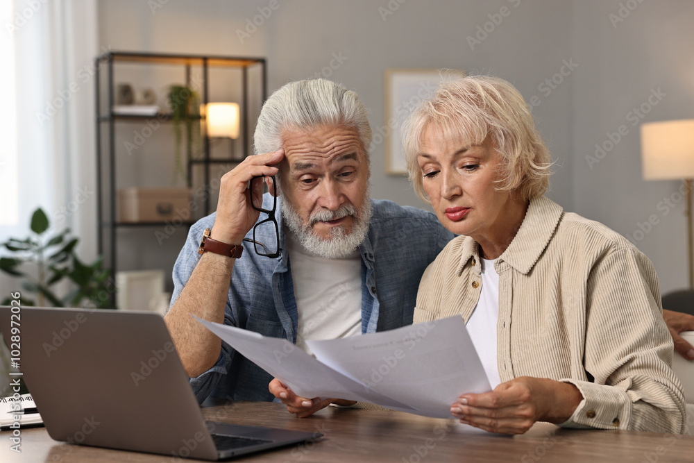 Pension savings. Senior couple planning budget at wooden table indoors Pension savings. Senior couple planning budget at wooden table indoors