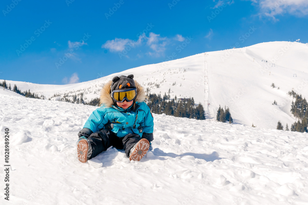 Little cute baby kid child boy sitting on snow winter hill,in ski alpine resort Carpathian high mountains nature landscape, travel,Ukraine, Europe Little cute baby kid child boy sitting on snow winter hill,in ski alpine resort Carpathian high mountains nature landscape, travel,Ukraine, Europe
