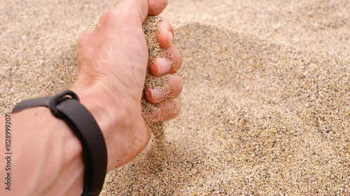 Time slips away like sand through your fingers. A man's hand pours sand on the beach