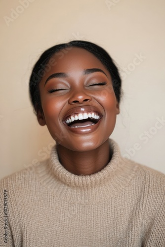 Close-Up Portrait of a Young Black Woman Laughing in Neutral Outfit photo