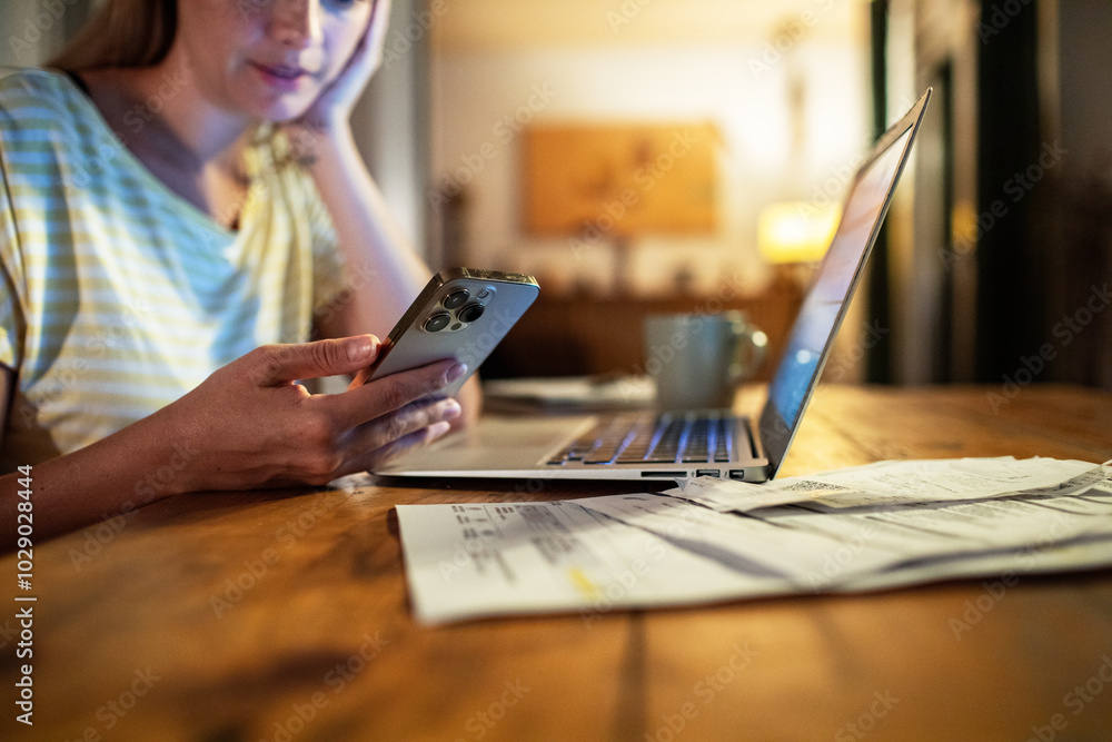 Fototapeta premium Woman late night working on laptop and smartphone at home