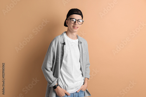 Portrait of smiling teenage boy on dark beige background