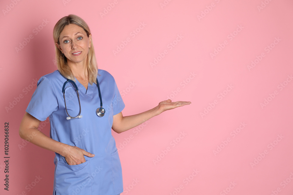 Portrait of doctor in medical uniform with stethoscope on pink background, space for text Portrait of doctor in medical uniform with stethoscope on pink background, space for text