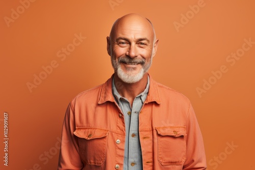 Portrait of a glad man in his 50s sporting a versatile denim shirt in front of pastel orange background