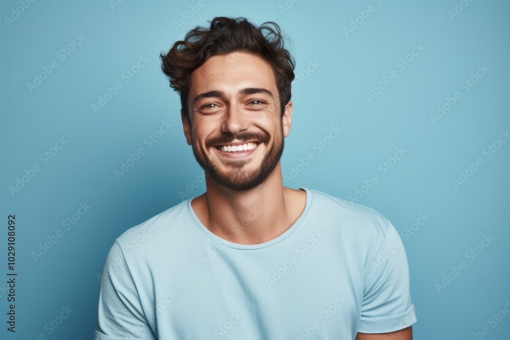 Portrait of a grinning man in his 20s donning a trendy cropped top in soft blue background Portrait of a grinning man in his 20s donning a trendy cropped top in soft blue background