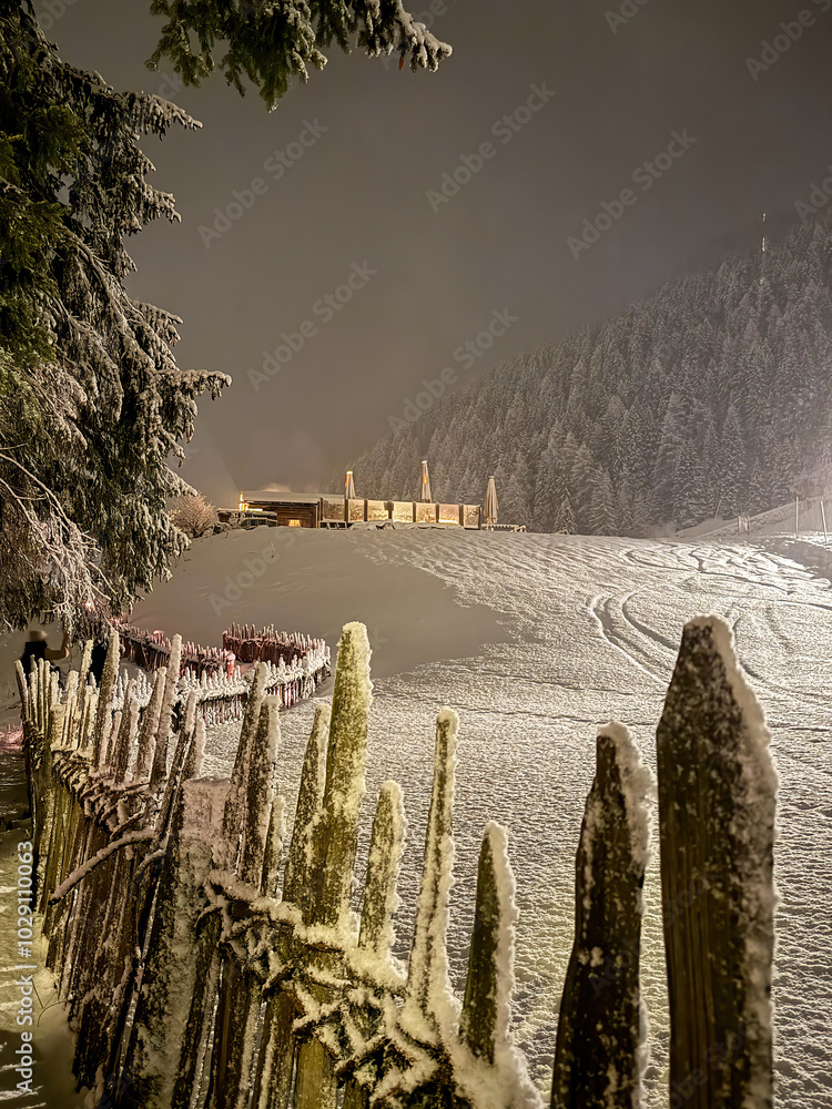 Illuminated winter landscape at night against cloudy sky