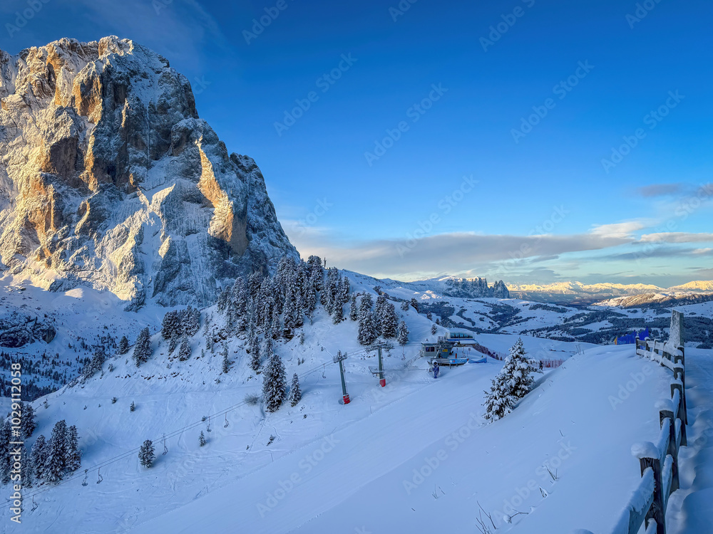 Langkofel mountain and Schlern in South Tyrol, Italy covered with snow at sunrise against blue sky with clouds