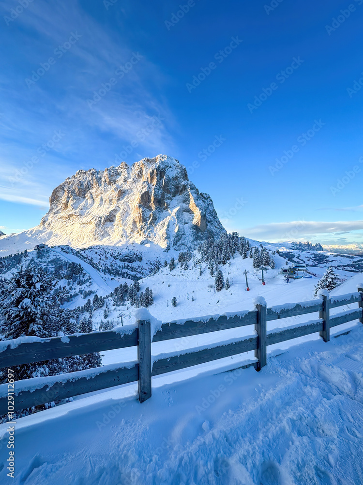 Langkofel mountain and Schlern in South Tyrol, Italy covered with snow at sunrise against blue sky with clouds