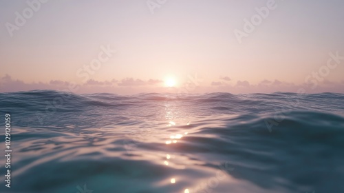 A calm ocean surface with soft waves reflecting the light of the setting sun.