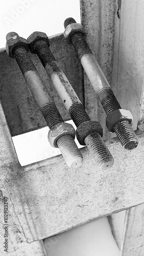 Three rusty old studs with nuts - a threaded bolt connection lie on a steel support. photo