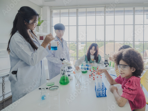 Child kid girl and boy asian young education student team group learning and smile have fun happy enjoy with science lab technology with in school class room has tubetest microscope chemicals  table photo