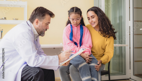 Doctor man care caucasian sitting use stethoscope check girl sick illness daughter who came to hospital with mother woman three people with talk helping support give advice inside  treatment room