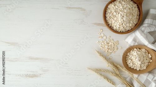 A top view of rolled oats in wooden bowls, with wheat stalks and a white background.