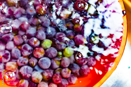 Blurred abstract overhead view of freshly picked grapes in a shimmering bowl of water photo