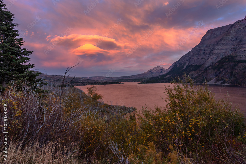 Fototapeta premium St. Mary Lake in Montana during the autumn season. Fancy clouds over water in pink light of sunset