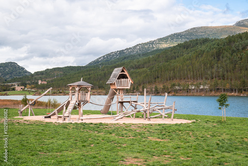 Fototapeta a playground in front of a lake and mountains