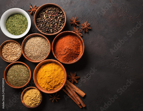 A set of spices and herbs. Indian cuisine. Pepper, salt, paprika, basil, turmeric. On a black wooden chalkboard. Top view. Free copy space.