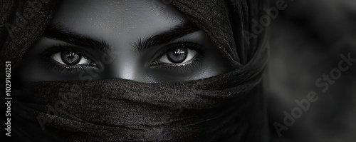 A close-up portrait of a veiled woman with only her captivating eyes visible through the dark fabric. The intense gaze, framed by the veil, creates a sense of mystery and beauty, ideal for fashion, my