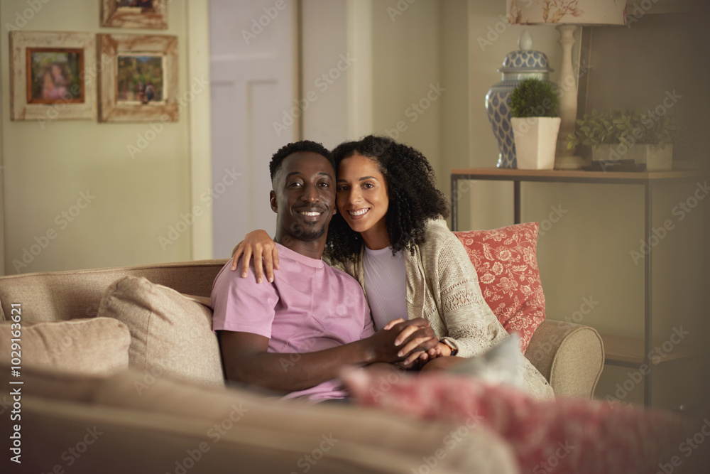 Smiling young multiracial couple sitting on their living room sofa Smiling young multiracial couple sitting on their living room sofa