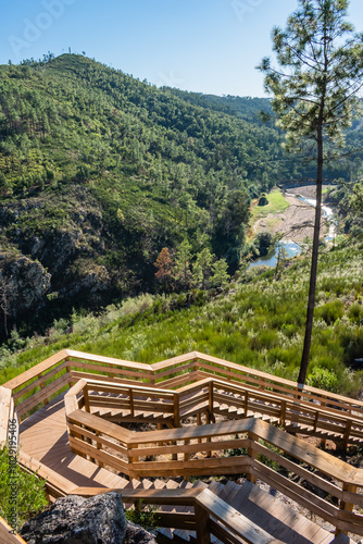 Fotografia Landscape with wooden walkways on the hill with vegetation and river in valley i