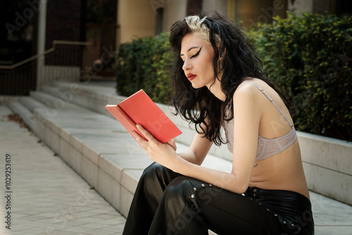 Relaxed edgy woman reading a book outdoors.