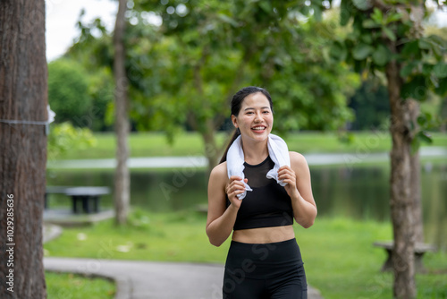 A woman is walking in a park with a towel in her hand