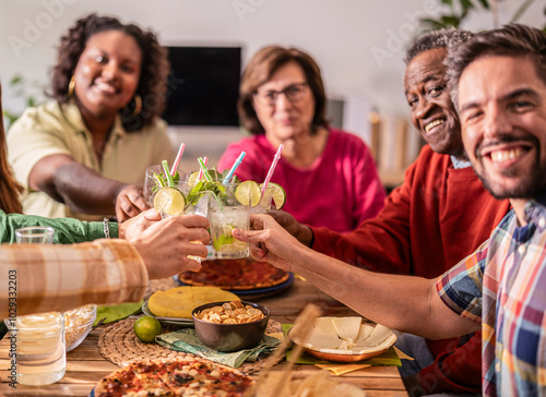 Group of friends making a toast at home with cocktails during lunch