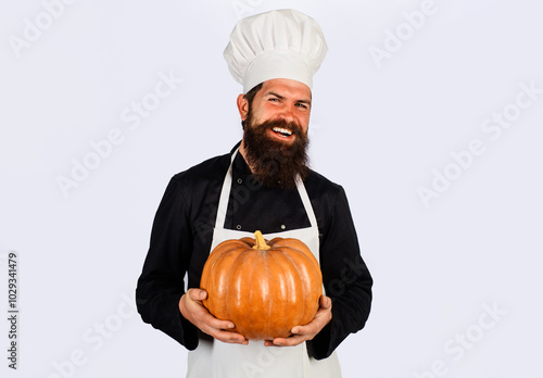 Smiling male cook in chef hat with pumpkin. Healthy vegetarian eating. Farm market. Autumn recipes. Bearded man in chef uniform with pumpkin for Halloween. Thanksgiving day cooking. Autumn vegetables.