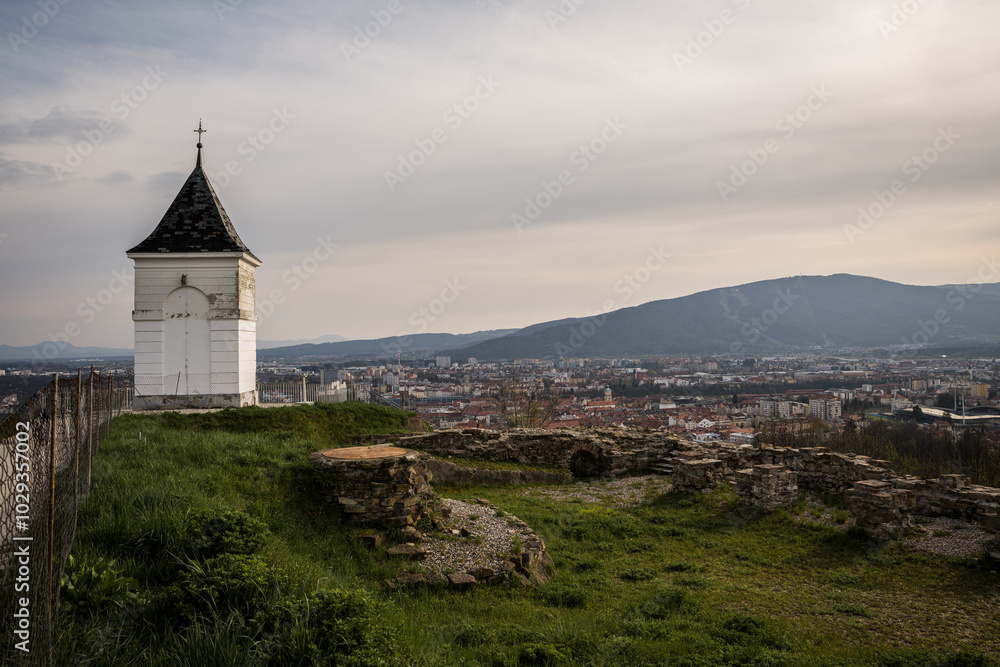 A panoramic view of Maribor, Slovenia, captured from Pyramid Hill (Piramida) during a serene spring afternoon, showcasing the city's red rooftops, sprawling streets, and surrounding landscape A panoramic view of Maribor, Slovenia, captured from Pyramid Hill (Piramida) during a serene spring afternoon, showcasing the city's red rooftops, sprawling streets, and surrounding landscape