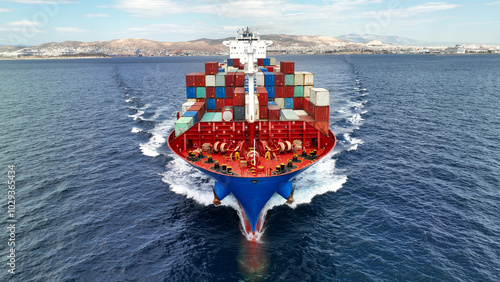 Aerial drone photo of colourful truck size container tanker ship cruising deep blue sea near commercial port of Piraeus, Attica, Greece