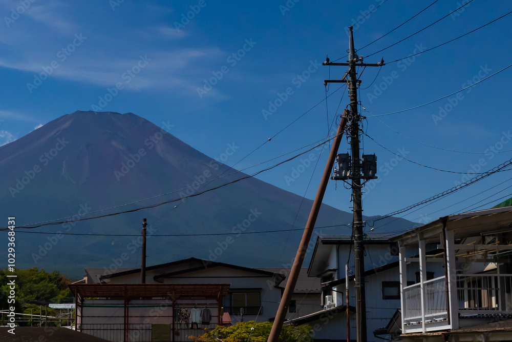 This is a beautiful image of Mount Fuji stretching up into the clear blue sky. White clouds can be seen around the base being blocked. This was shot in Fujiyoshida Japan among the town. This is a beautiful image of Mount Fuji stretching up into the clear blue sky. White clouds can be seen around the base being blocked. This was shot in Fujiyoshida Japan among the town.