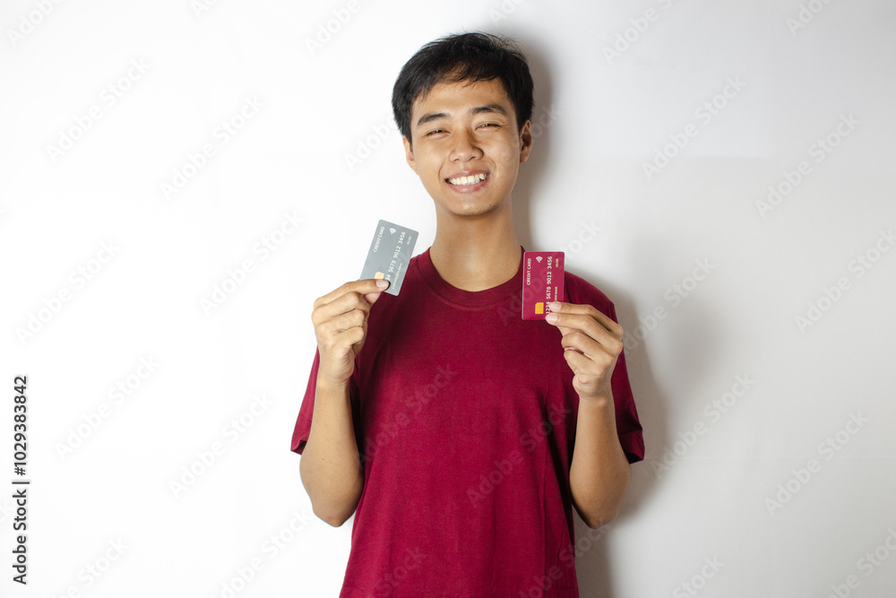 a teenager smiling cheerfully with two credit cards in his hands a teenager smiling cheerfully with two credit cards in his hands