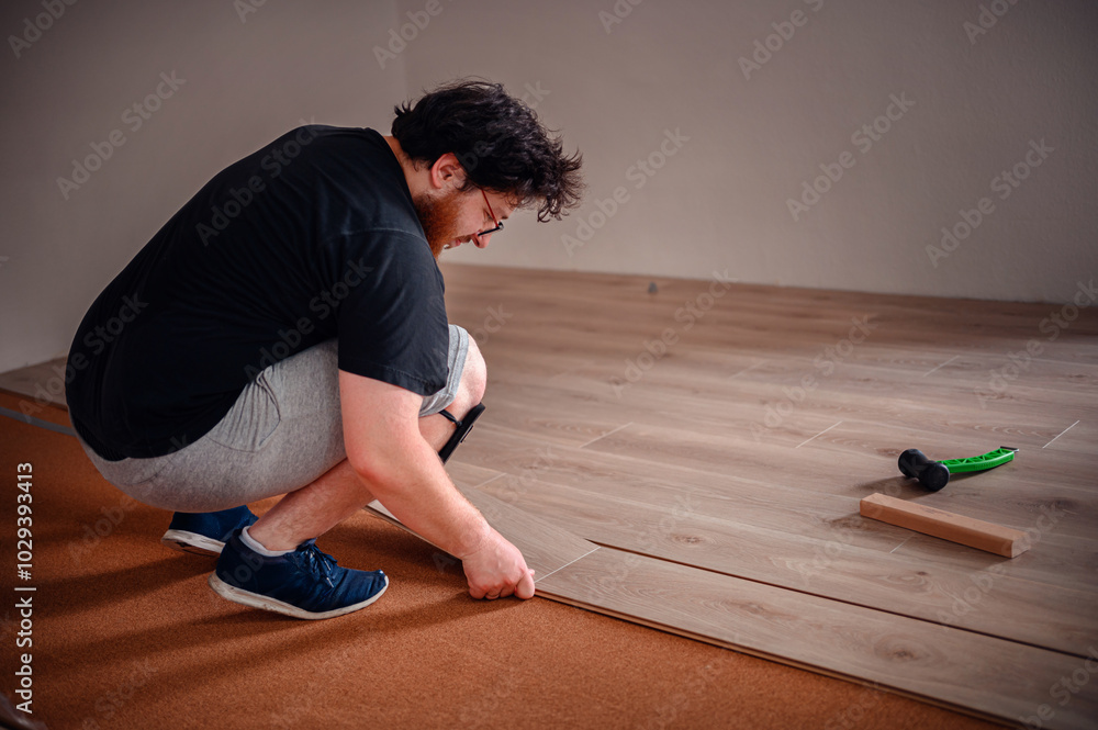 Man Installing Laminate Flooring with Tools Man Installing Laminate Flooring with Tools
