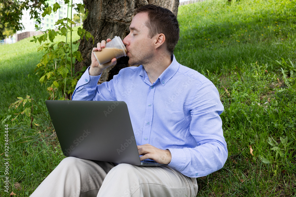 Employee with a laptop having coffee break outside in the park Employee with a laptop having coffee break outside in the park