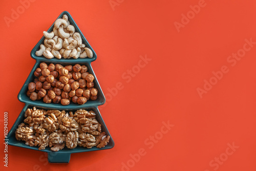 different types of nuts, Various snacks for the New Year table in a plate in the shape of a Christmas tree.