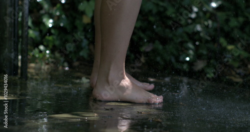 Bare feet on wet ground with water splashing around, slow-motion capture highlighting the dynamic interaction and natural refreshment