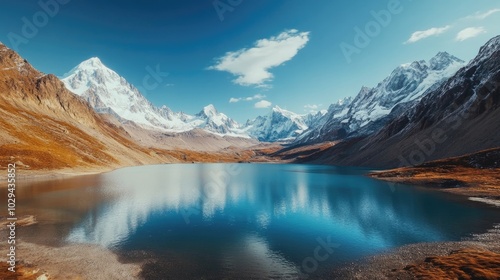 A wide-angle view of a pristine lake bordered by snow-capped mountains under a clear day.