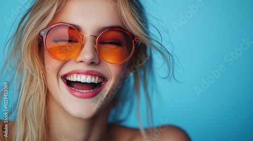 A joyful woman with sunglasses smiling against a vibrant blue background in bright sunlight