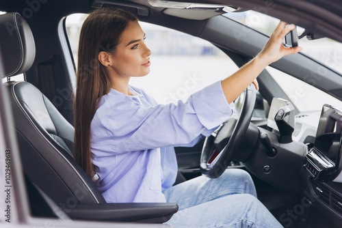 Young Woman Adjusting Rearview Mirror While Driving Modern Car