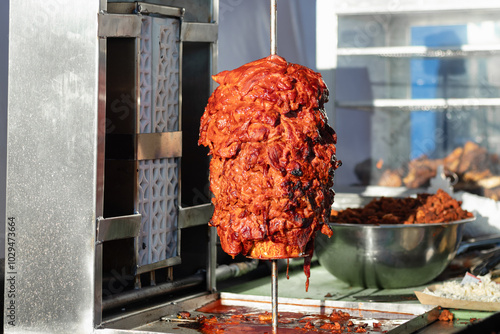 Pork al pastor meat, marinated and roasting on a rustic grill, for the preparation of authentic al pastor tacos, in an open-air Mexican food restaurant in a market photo