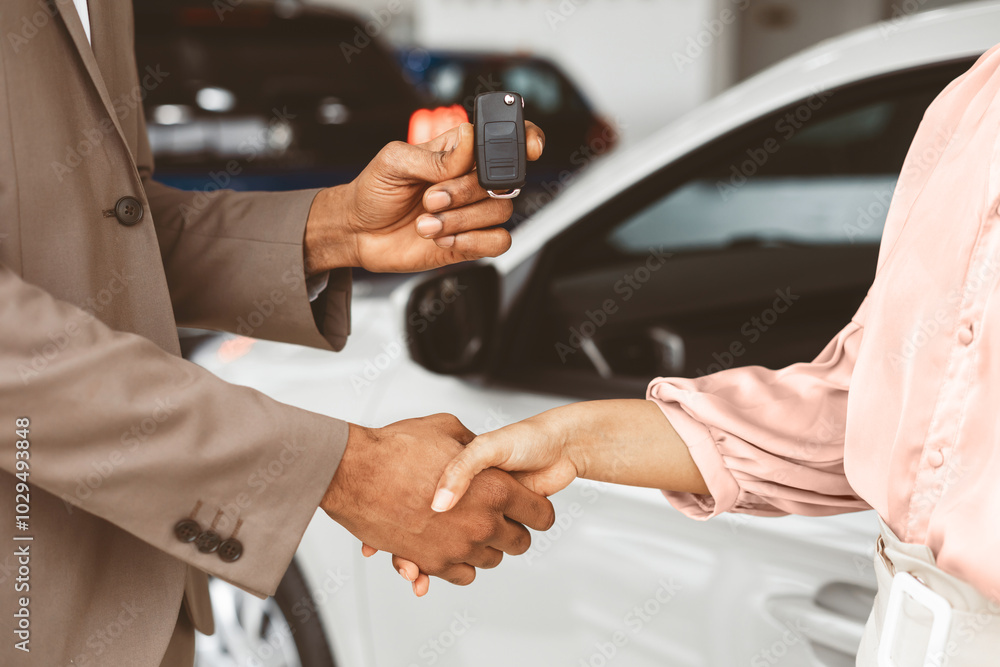 Car Sales. Unrecognizable Seller Greeting Lady Buyer With Handshake And Giving Key Standing Near Automobile In Dealership Store. Cropped Car Sales. Unrecognizable Seller Greeting Lady Buyer With Handshake And Giving Key Standing Near Automobile In Dealership Store. Cropped