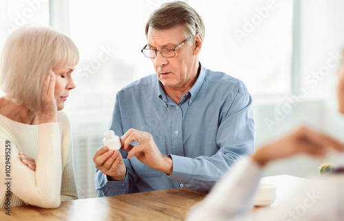 Medical Prescription. Senior man with his wife looking at pills at doctor's office, copyspace