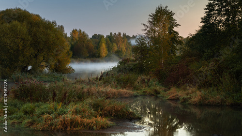 marshy area with many ponds, lakes and lush coastal thickets in the pre-dawn hours with fog over the water. multi-plane autumn landscape in 16x9 format photo