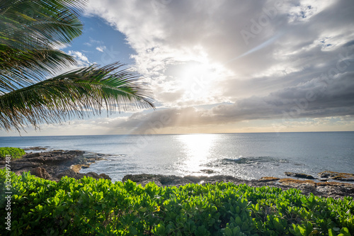 Tranquil coastal scene with the sun casting a golden glow over the calm ocean. 