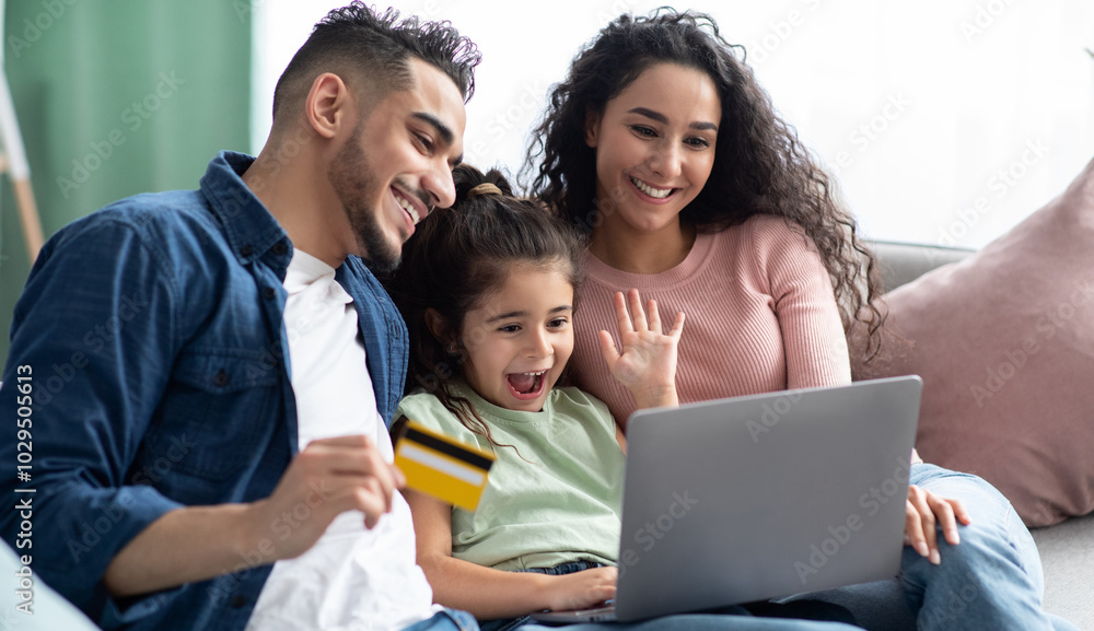 Cheerful Arabic Family Of Three With Laptop And Credit Card Making Online Shopping While Relaxing On Couch At Home, Happy Middle Eastern Parents And Little Daughter Enjoying Purchase From Internet Cheerful Arabic Family Of Three With Laptop And Credit Card Making Online Shopping While Relaxing On Couch At Home, Happy Middle Eastern Parents And Little Daughter Enjoying Purchase From Internet